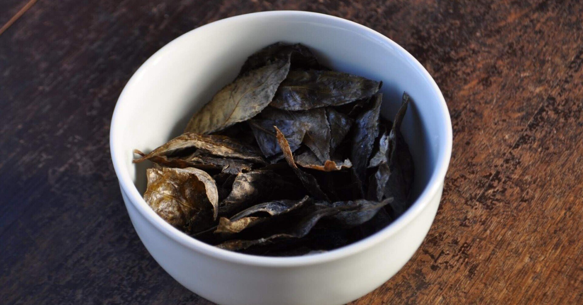 Finished Bodai-Sancha leaves in a white bowl, showing the dark color after lactic fermentation